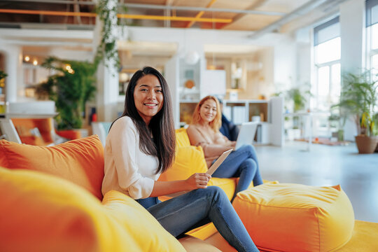 Asian women seating in comfortable sofa in coworking office. Generative AI