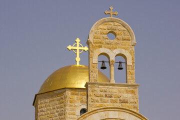 Golden dome with cross and wall with bells. Modern Orthodox Church of John Baptist next to site of baptism of Jesus Christ in Jordan. Al-Makhtas