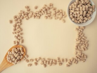 Extruded bran on a wooden spoon and in a white plate. The bran is scattered around the frame...