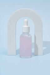 Beauty collagen face serum in a glass dropper bottle in Arch on light blue background. Trendy shoot of cosmetics packaging. Essential oil with natural ingredients.