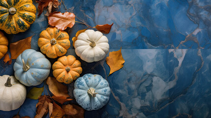 A group of pumpkins with dried autumn leaves and twig, on a blue color marble
