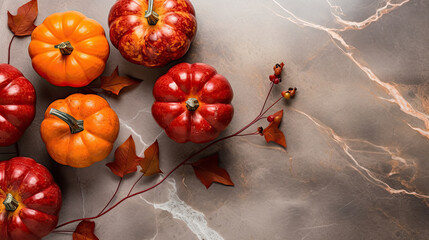 A group of pumpkins with dried autumn leaves and twig, on a scarlet color marble - obrazy, fototapety, plakaty