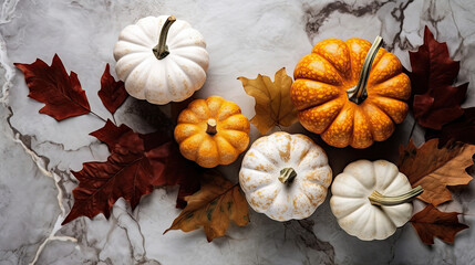 A group of pumpkins with dried autumn leaves and twig, on a dark white color marble