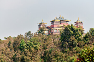Tibetan temple on mountain shrouded in green vegetation amidst peaceful nature inviting visitors to...