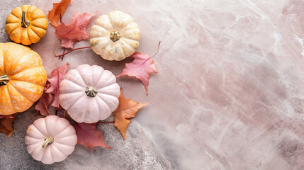A group of pumpkins with dried autumn leaves and twig, on a light pink color marble
