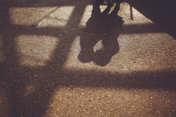 A persons shadow falls on the wooden floor, creating tints and shades