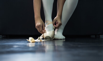 Ballet dancer wearing satin pointe ballet shoes preparing for ballet performance