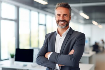 Confident male entrepreneur smiling while standing with arms crossed at office