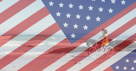 Image of american flag revealing statue of liberty and woman riding bike on beach