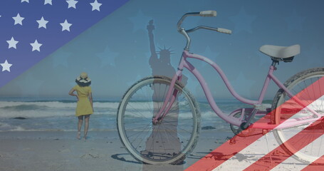 Image of american flag revealing statue of liberty and woman walking on beach