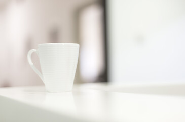 White coffee mug on counter desk in reception room with real natural bright daylight
