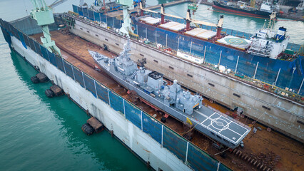 war ship maintenance in dry dock shop. War Ship floating on dry dock. Military navy ship get...