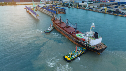 Tug boat pulling cargo container ship to dry dock concept maintenance service working in the sea....