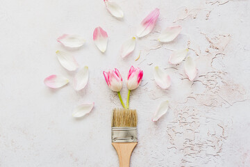 Ein Farbpinsel mit rosa Tulpen und Blütenblättern auf einem grauen Hintergrund. Flat lay.