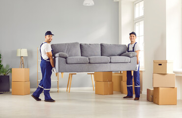 Movers male professional team in overalls loading, place furniture sofa at new location with care,...