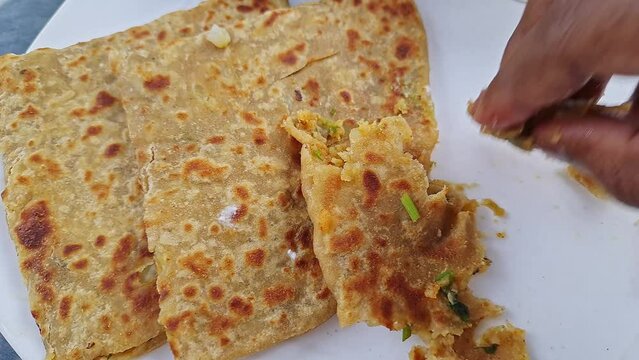 Top view of eating popular Indian food aloo paratha or potato stuffed flat bread