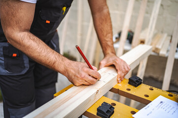 Unrecognizable men measuring wooden plank outdoors