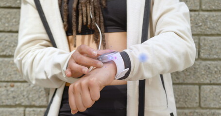 Image of light beam and lens flare over midsection of woman using smartwatch
