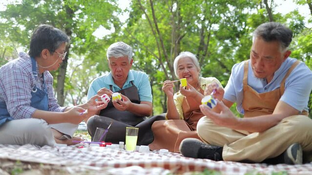 Art activities for the elderly. A group of elderly people sit and paint pots in the garden outside. They are happy. Living happily in retirement. art therapy. Elderly community