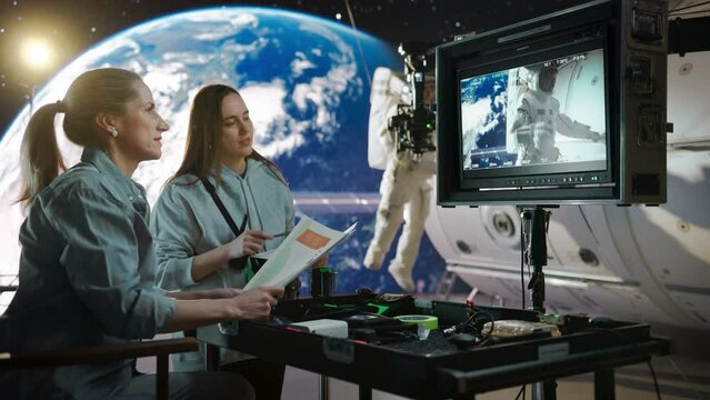 Two Young Women Working in a Virtual Production Studio with Big Led Panel Screen. Talented Female Film Director Having a Conversation with a Studio Set Assistant During an Space Action Movie Shoot