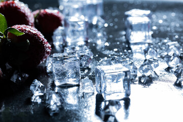 Spilled ice cubes close-up lying on a dark and wet countertop, next to beautiful and fresh...