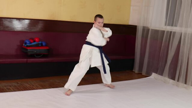 Boy athlete with blue belt performs formal exercises