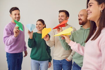 Team of happy, smiling, young, casual people playing with paper planes. Group of cheerful men and...