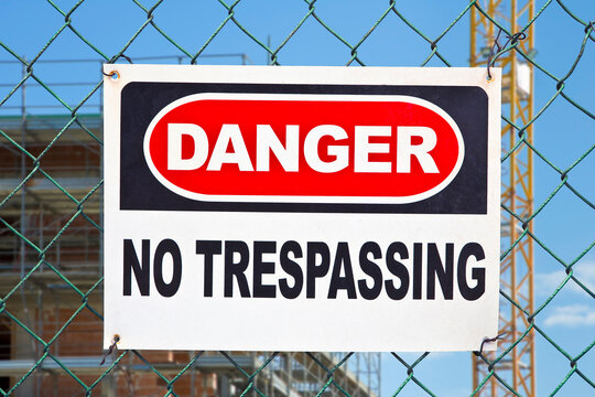 Information with warning sign and no trespassing signboard against a wire mesh of a construction site