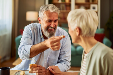 A close-up shot of an affectionate old married couple being playful with each other during breakfast
