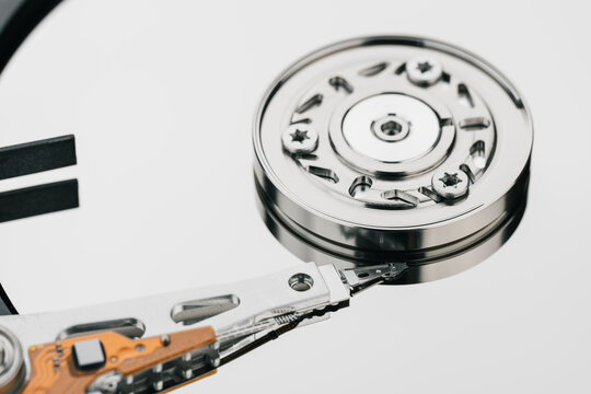 Hard drive isolated on white background. HDD. Major components of a 3.5-inch SATA hard disk drive: platter, spindle, actuator, actuator arm. Disk head above the plates	
