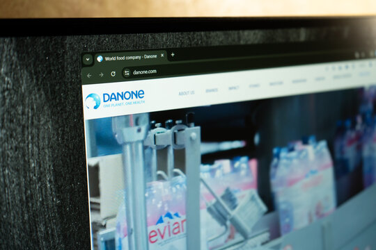 Ukraine. Dnepr 01.25.2024: Person holding mobile phone with logo of French food company Danone S.A. on screen in front of business web page. Danone logo on the website homepage.