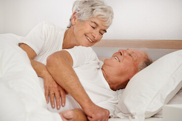 Senior couple, hug and communication in bed, relaxing and love in retirement for bonding on weekend. Happy elderly people, conversation and embracing in marriage, romance and morning routine at home
