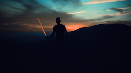 spectacular sunset in the mountains with the silhouette of a man holding a laser sword