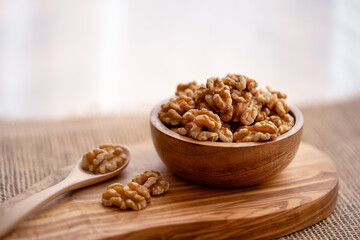 Walnuts in a wooden bowl on a wooden board. Wooden spoon with peeled walnuts