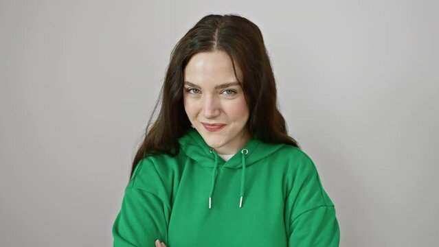 Flirty fun, young woman winking at the camera with a radiant smile, standing against an isolated white background, wearing a sweatshirt. her expression, cheerful and sexy!
