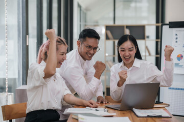 Enthusiastic Asian business team celebrating a successful project in office. Group achievement and teamwork concept.