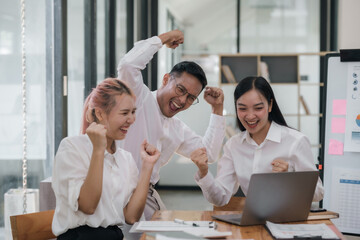 Enthusiastic Asian business team celebrating a successful project in office. Group achievement and teamwork concept.