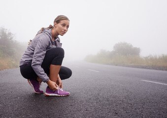 Fitness, woman and tie shoes on road outdoor to prepare for exercise, training or workout with fog...