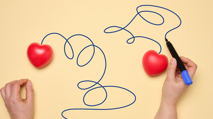 Two red hearts on a yellow background, a woman's hand draws a trajectory