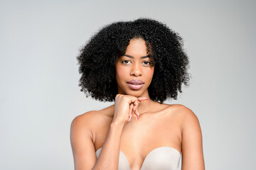 An African-American woman with striking natural curls and a thoughtful expression poses in a...