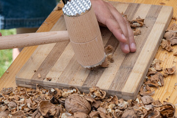 Man cracking walnuts with hammer at table, closeup
