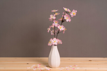 グレーの背景に花瓶に生けた桜の花
