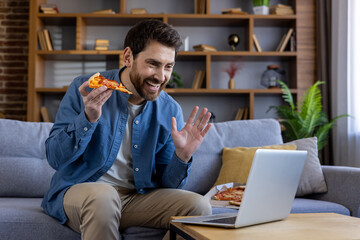 Cheerful man enjoying pizza slice during video call at home, casual lifestyle