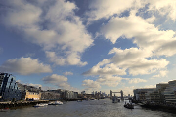 Puffy white clouds drift over central London as seen looking down the Thames towards tower bridge.