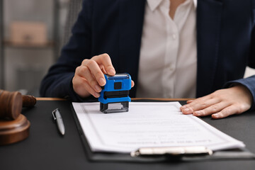 Notary stamping document at table in office, closeup