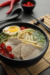 Delicious ramen with meat in bowl served on grey table, closeup. Noodle soup