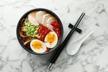 Delicious ramen in bowl and spoon on white marble table, flat lay. Noodle soup