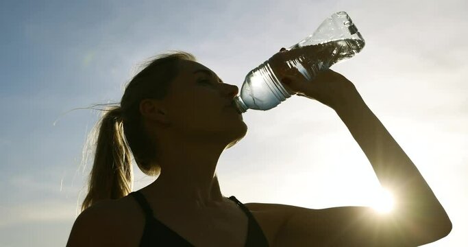 sporty woman drinking water from bottle after outdoor fitness workout