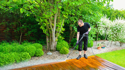 man cleaning terrace with a power washer - high water pressure cleaner on wooden terrace surface - 741480357