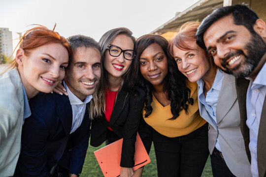 Multiracial group of businesspeople taking a selfie together with coworkers in the office after finishing brainstorming